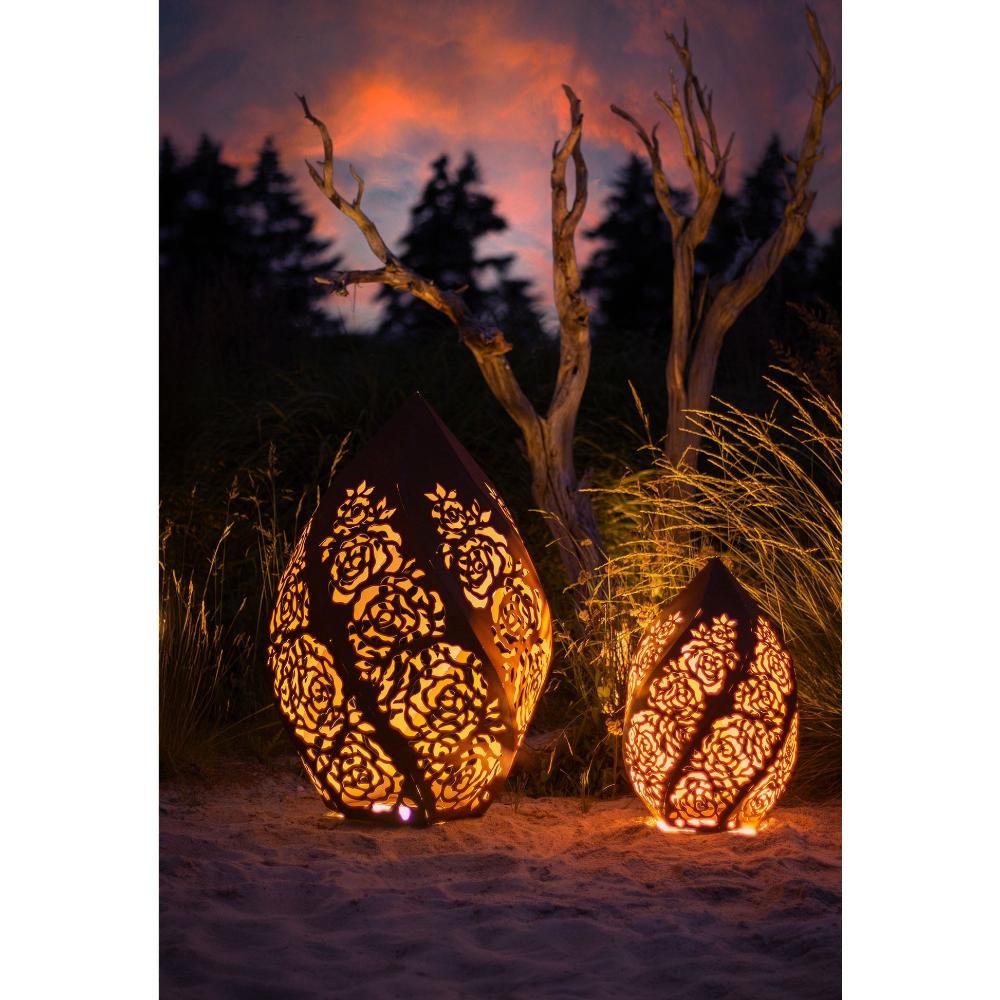 „Windlicht Rosentraum Edelrost in der Abenddämmerung, verleiht dem Garten eine romantische und einladende Atmosphäre“